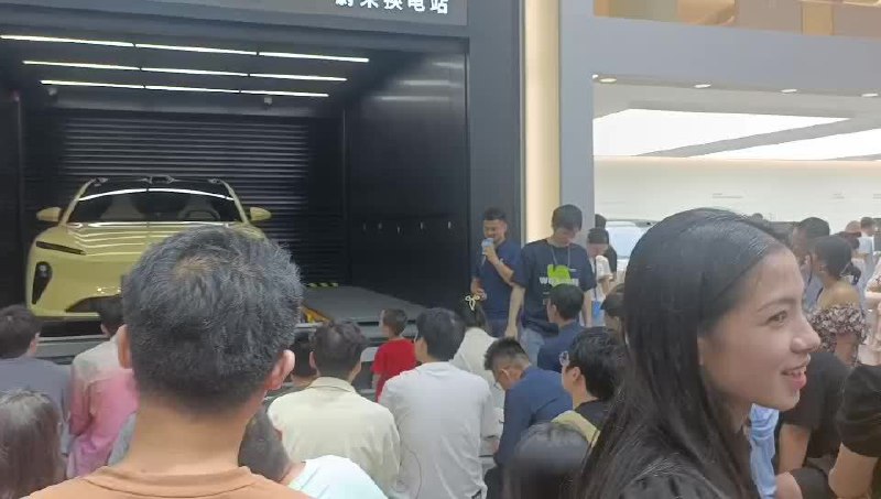蔚来的展台很受欢迎，工作人员正在详细地讲解换电过程，每次换电全过程用时 3 分钟，间隔一分钟讲解一轮，吸引了不少观众围观。配图